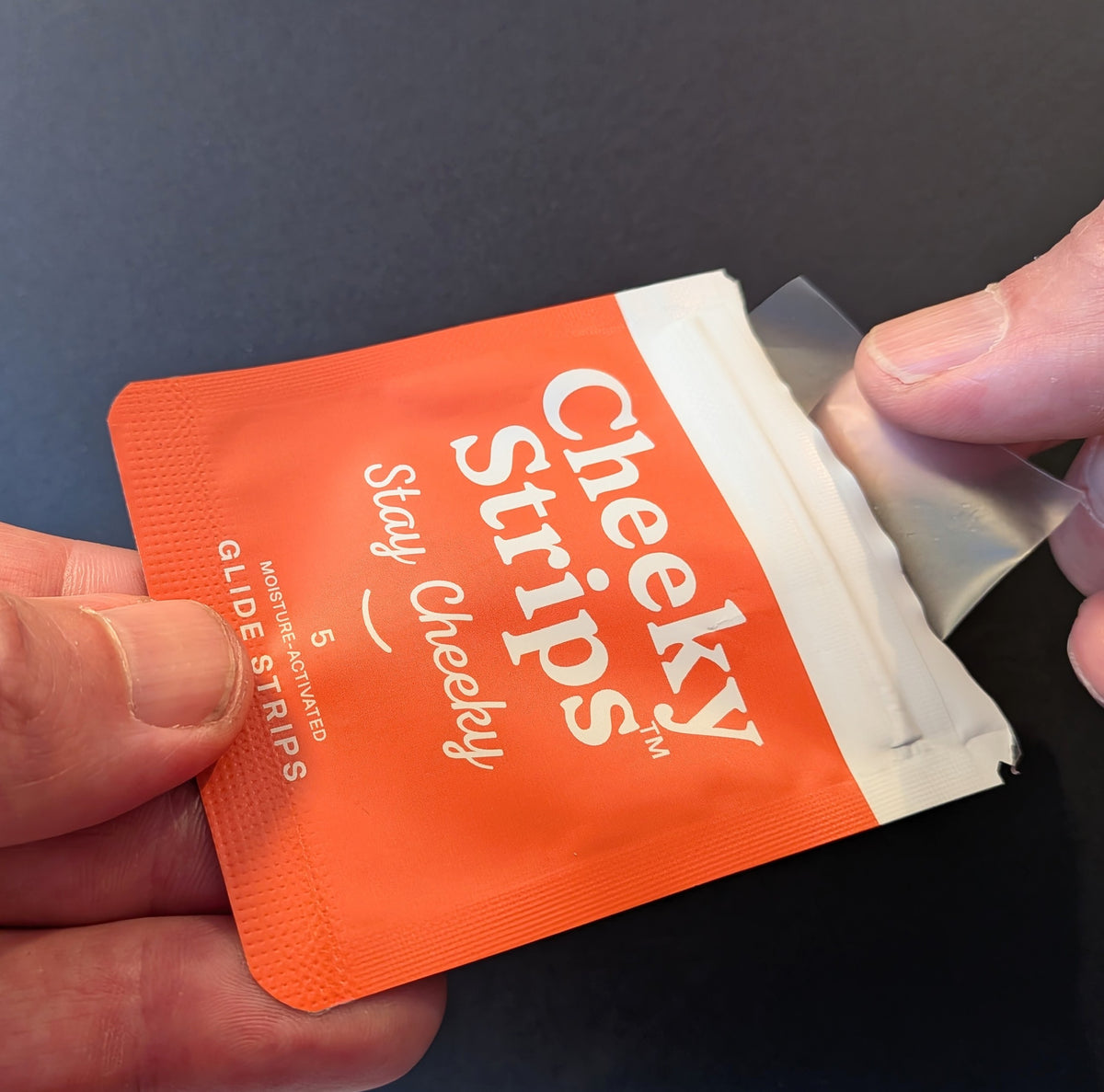 Clear glide strip being pulled from a Cheeky Strips pouch